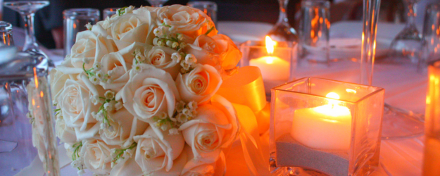 A traditional Greek wedding bouquet laying on a table with candles